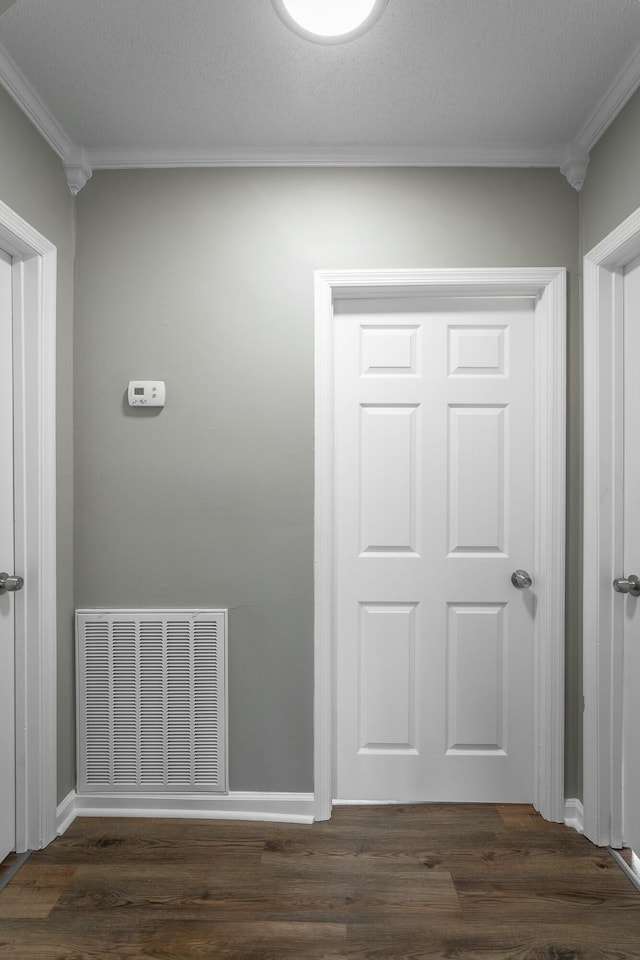 hallway featuring visible vents, baseboards, dark wood-type flooring, and crown molding