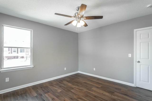 spare room with dark wood-style floors, a ceiling fan, and baseboards