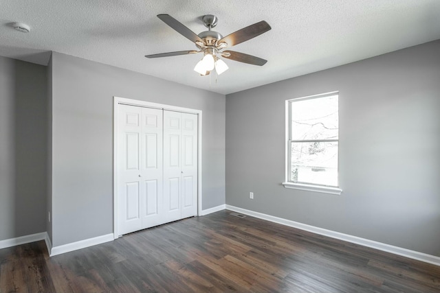 unfurnished bedroom with baseboards, visible vents, dark wood-type flooring, a closet, and a textured ceiling