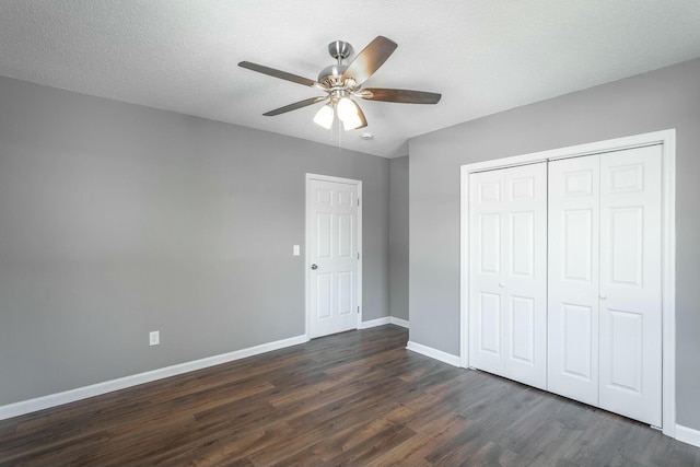 unfurnished bedroom featuring a ceiling fan, baseboards, dark wood-style flooring, a closet, and a textured ceiling