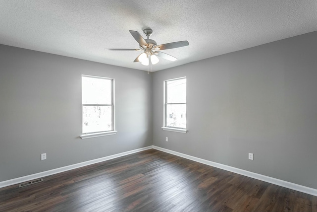 unfurnished room with a ceiling fan, dark wood-style floors, visible vents, and baseboards