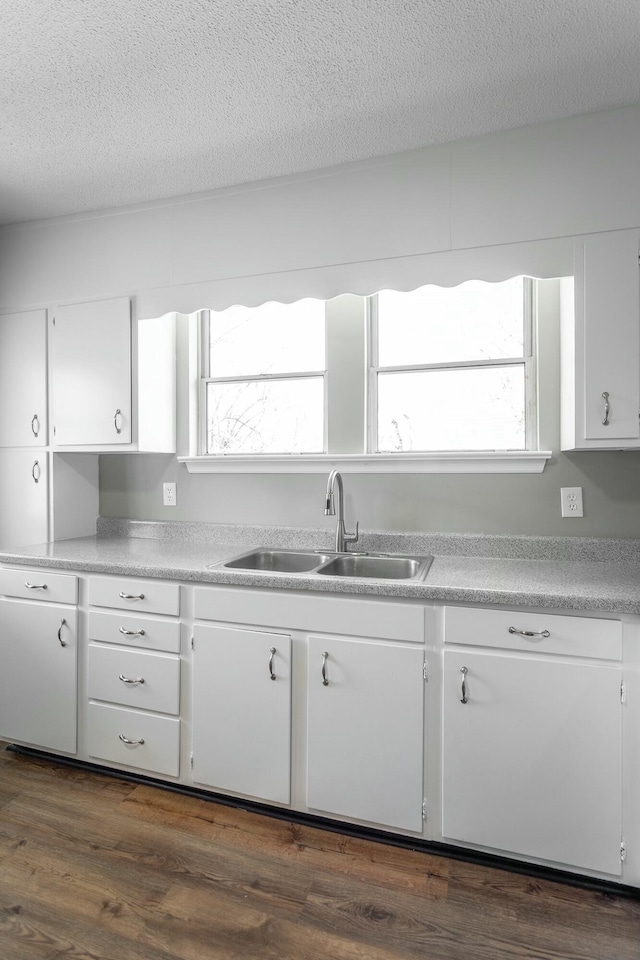 kitchen featuring a sink, a textured ceiling, dark wood-style floors, white cabinetry, and light countertops