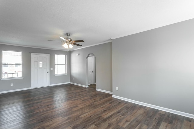 unfurnished living room featuring ornamental molding, a ceiling fan, arched walkways, baseboards, and dark wood-style flooring