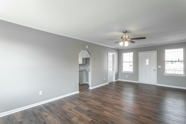 unfurnished living room featuring crown molding, baseboards, arched walkways, a ceiling fan, and dark wood-style flooring