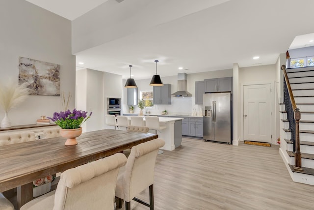 dining room featuring recessed lighting, light wood-style floors, and stairs