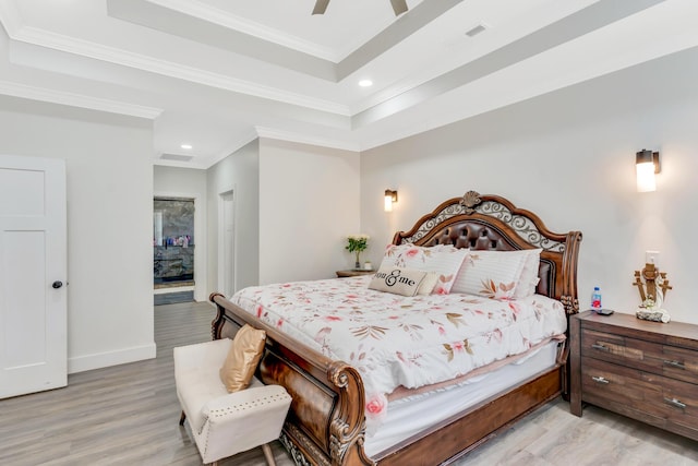 bedroom featuring visible vents, crown molding, light wood-type flooring, and a tray ceiling