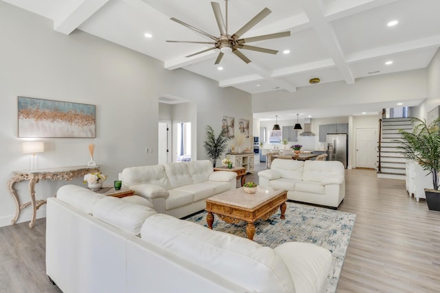 living area featuring ceiling fan, beamed ceiling, stairway, light wood-style flooring, and recessed lighting