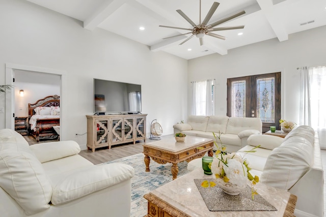 living room with light wood-style flooring, plenty of natural light, beamed ceiling, and ceiling fan