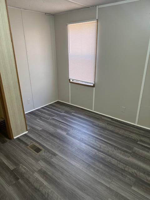 unfurnished bedroom featuring dark wood finished floors and visible vents