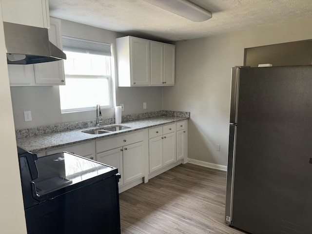 kitchen with a sink, white cabinets, black electric range oven, and freestanding refrigerator