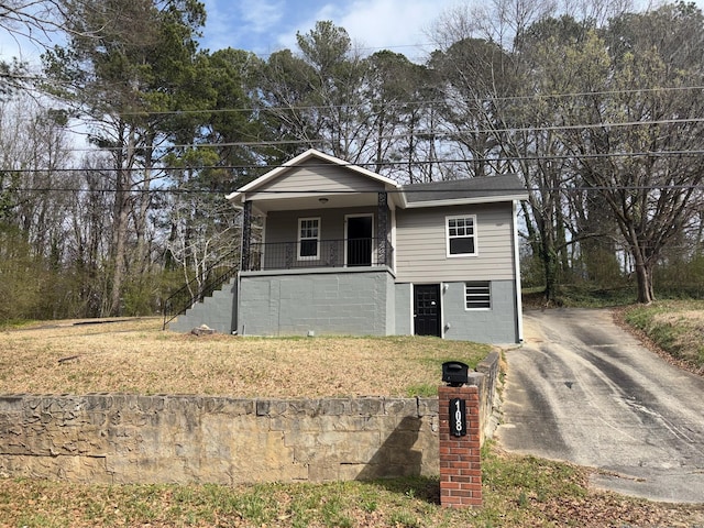 view of front facade with a porch, driveway, stairs, and a front lawn