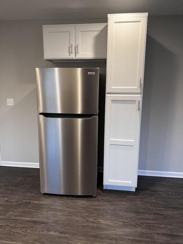 kitchen with baseboards, white cabinetry, dark wood-type flooring, and freestanding refrigerator