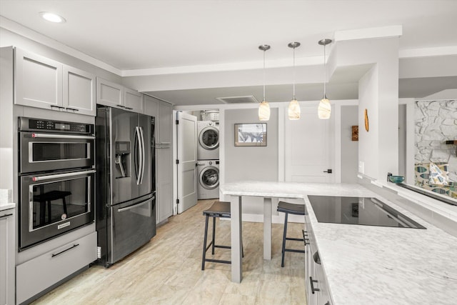 kitchen with double oven, light countertops, stacked washer and dryer, stainless steel fridge, and black electric cooktop