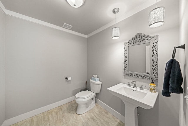 half bathroom with visible vents, toilet, ornamental molding, a sink, and baseboards