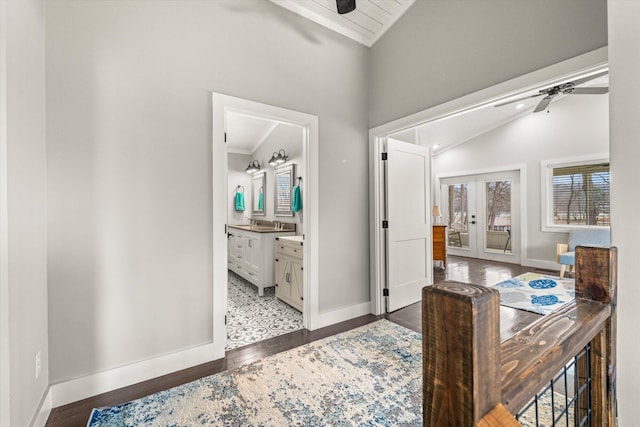 corridor with french doors, wood-type flooring, baseboards, and vaulted ceiling