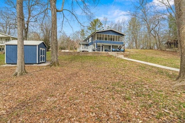 view of front of house featuring a front yard, a patio, a sunroom, an outdoor structure, and a storage shed