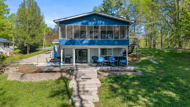 back of property featuring stairs, a patio area, a lawn, a sunroom, and a deck