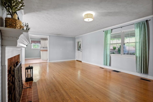 unfurnished living room featuring plenty of natural light, visible vents, and ornamental molding