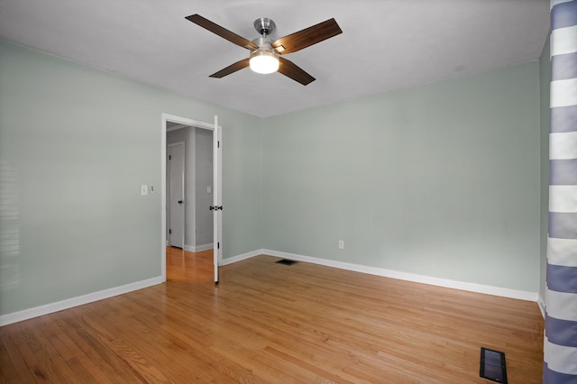 spare room with ceiling fan, baseboards, visible vents, and wood finished floors