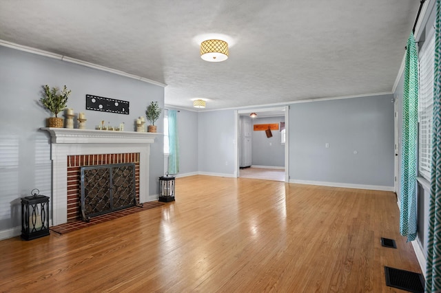unfurnished living room with crown molding, wood finished floors, visible vents, and a fireplace