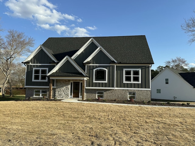 view of front of house with board and batten siding, a front yard, and a shingled roof