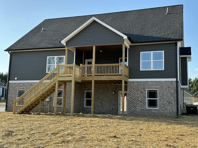 back of property with brick siding, a wooden deck, stairs, and roof with shingles