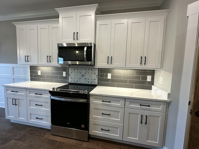 kitchen featuring tasteful backsplash, stainless steel microwave, crown molding, black range with electric stovetop, and white cabinetry