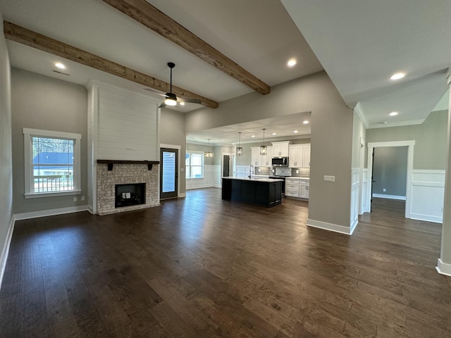 unfurnished living room with a wealth of natural light, a large fireplace, and dark wood-type flooring