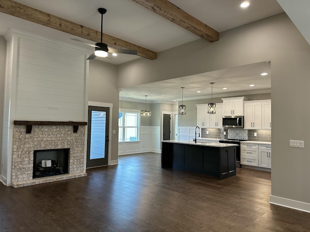 kitchen featuring ceiling fan, open floor plan, beam ceiling, appliances with stainless steel finishes, and dark wood-style flooring