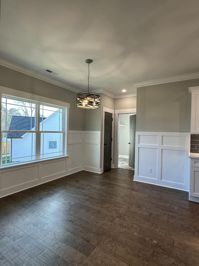 unfurnished dining area with crown molding, an inviting chandelier, dark wood-style flooring, and a decorative wall