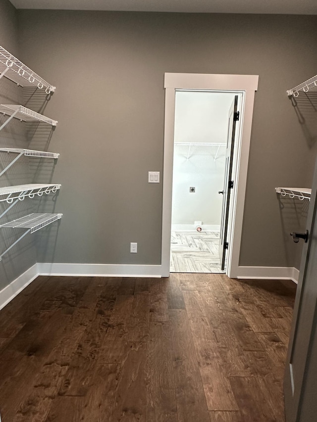 walk in closet with dark wood-style flooring