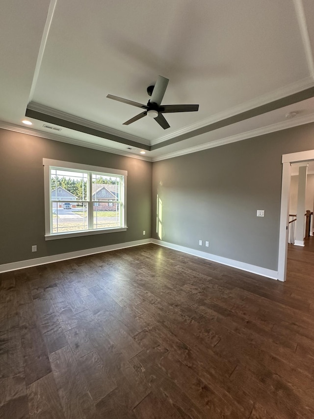 empty room with a tray ceiling, a ceiling fan, visible vents, and dark wood-style flooring