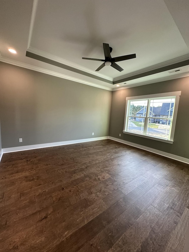 empty room featuring a raised ceiling, crown molding, a ceiling fan, and dark wood-style flooring