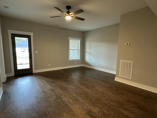 unfurnished room with visible vents, baseboards, dark wood-type flooring, and a ceiling fan