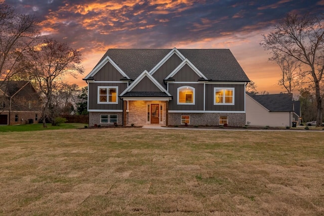 view of front of house featuring brick siding, board and batten siding, and a front yard