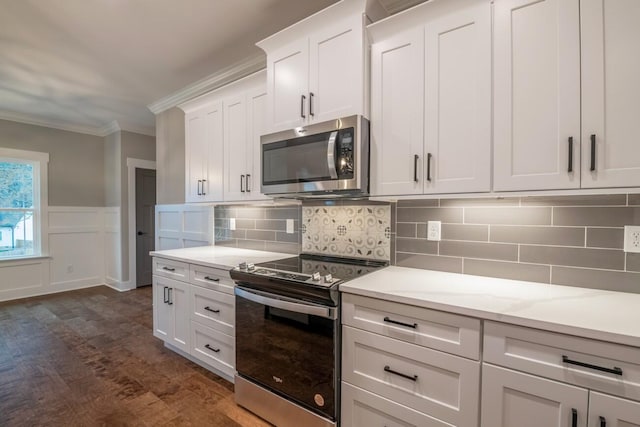kitchen with crown molding, white cabinetry, appliances with stainless steel finishes, decorative backsplash, and dark wood-type flooring