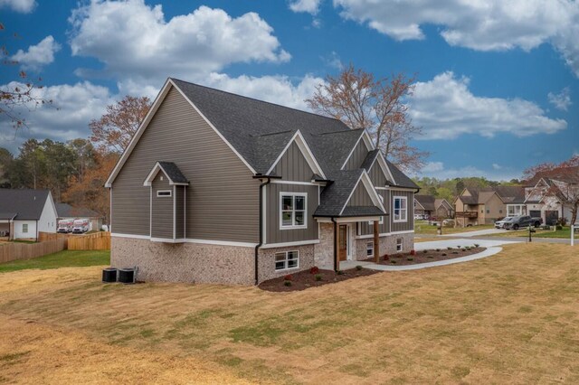 craftsman-style home with fence, board and batten siding, a residential view, a front yard, and a shingled roof
