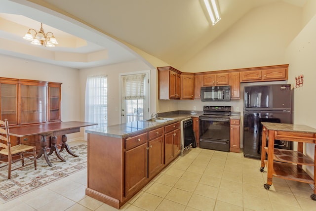 kitchen with dark countertops, a chandelier, black appliances, a raised ceiling, and a sink