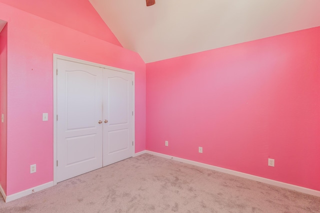 unfurnished bedroom with lofted ceiling, a ceiling fan, a closet, carpet, and baseboards