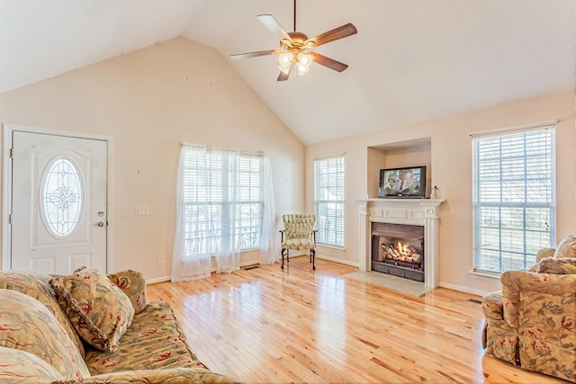 living room featuring a fireplace with flush hearth, high vaulted ceiling, light wood-style floors, and ceiling fan