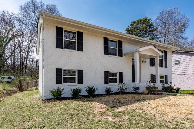 raised ranch with brick siding and a front yard