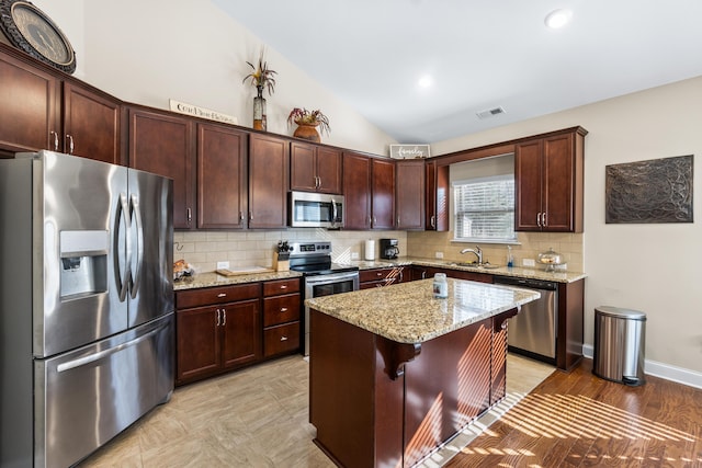 kitchen with visible vents, backsplash, lofted ceiling, stainless steel appliances, and a sink