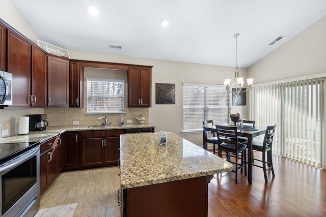 kitchen featuring visible vents, lofted ceiling, a sink, stainless steel appliances, and a chandelier