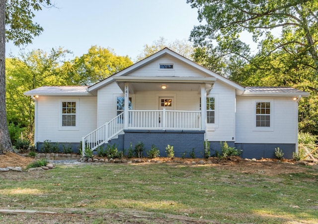 view of front facade featuring metal roof, covered porch, a front lawn, and stairway