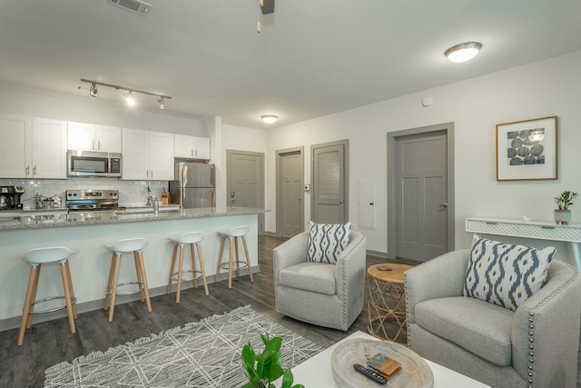 living area featuring wood finished floors, visible vents, and baseboards