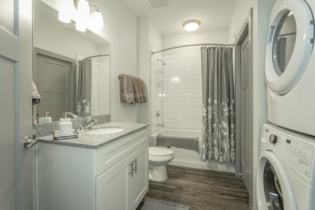 full bathroom with vanity, wood finished floors, shower / bath combo, stacked washer / dryer, and toilet