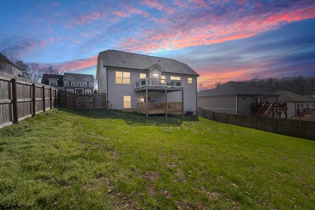 back of house with a lawn, a fenced backyard, a balcony, and a wooden deck