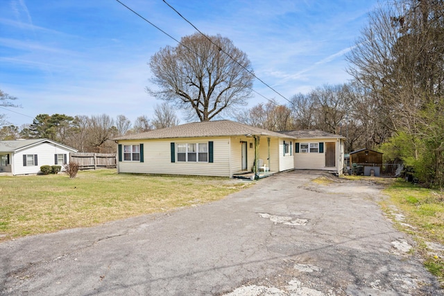 ranch-style house with a front yard, driveway, and fence