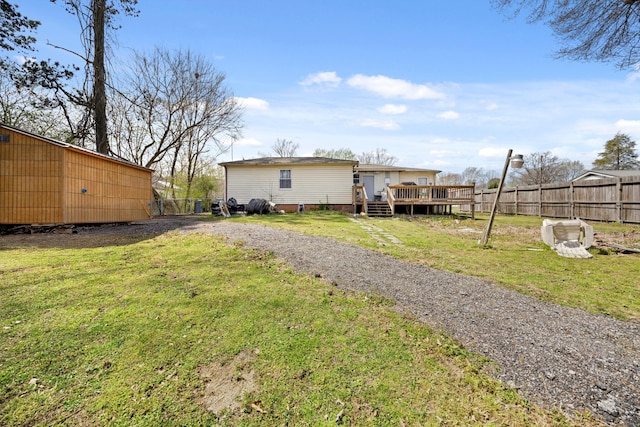rear view of property with a lawn, fence, and a wooden deck