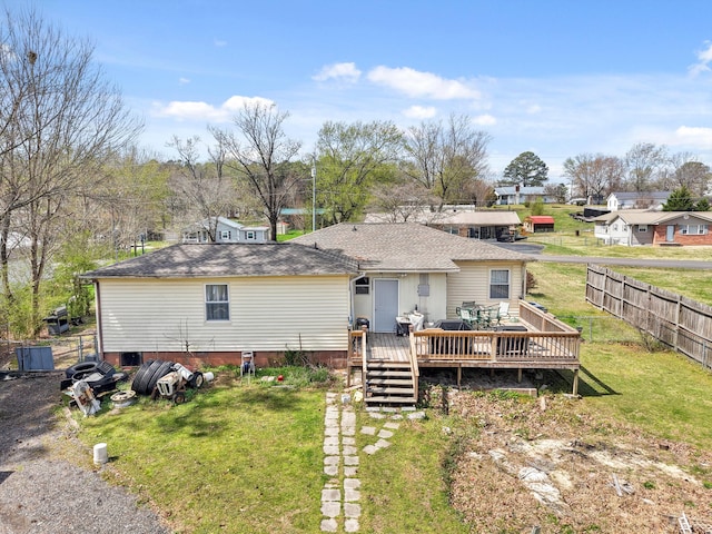 back of property with fence, a shingled roof, a yard, and a wooden deck